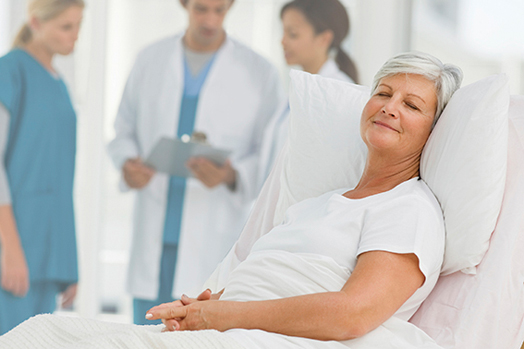 Patient lying on a bed with relief while doctors standing togeth